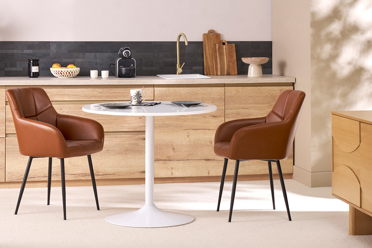 Sedie imbottite marroni e metallo nero MONTERO intorno a un tavolo bianco.