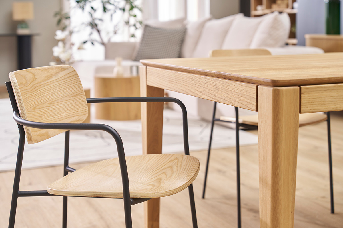 Sedie Susan in legno chiaro con gambe in metallo nero accanto a un tavolo in legno.