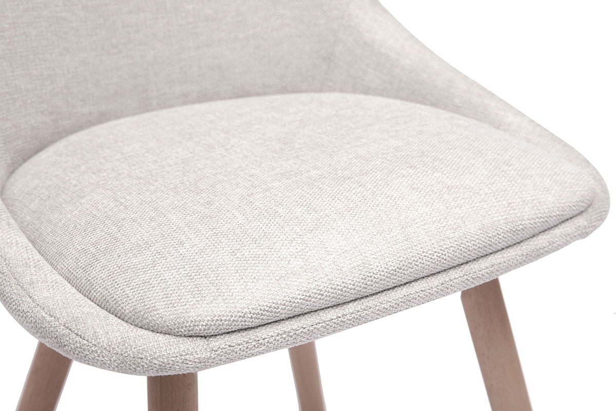 Primo piano sul sedile imbottito di una sedia in tessuto effetto velluto beige e gambe in legno chiaro.