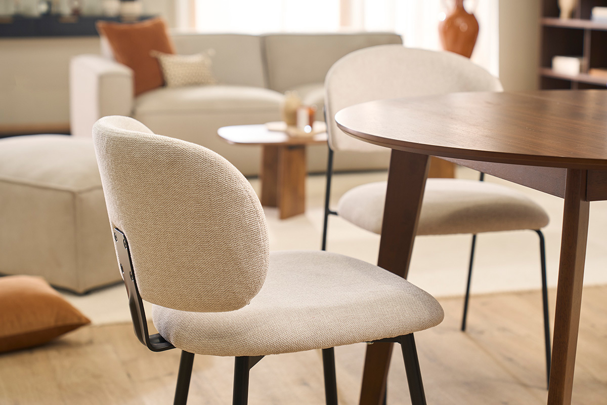 Sedie ATRIUM in tessuto beige e metallo nero intorno a un tavolo in legno.