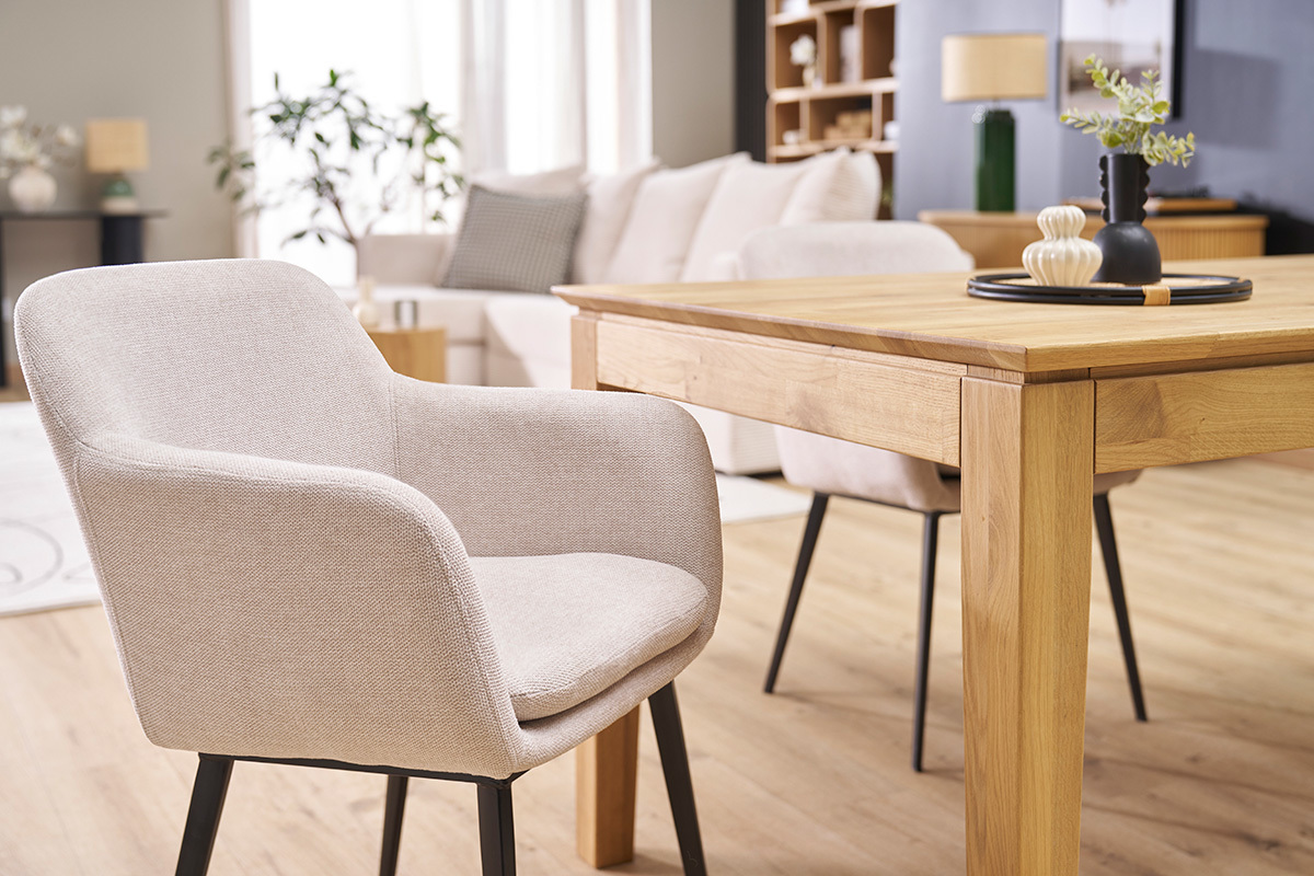 Sedie in tessuto beige effetto velluto e metallo nero, intorno a un tavolo in legno in un soggiorno contemporaneo.