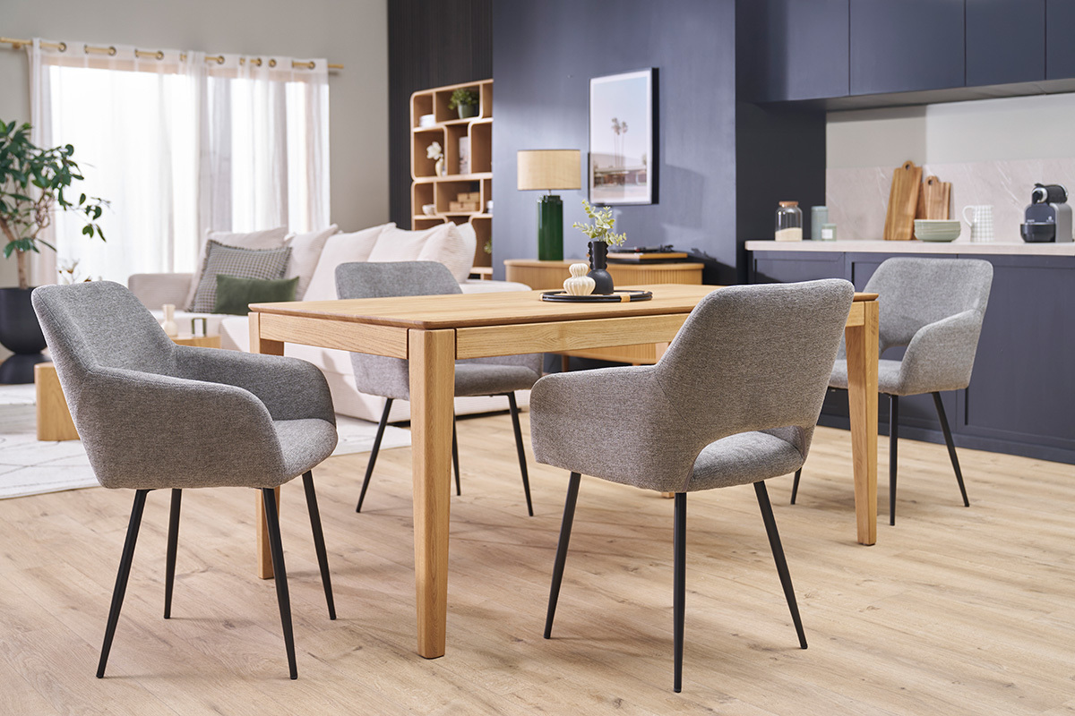Quattro sedie LAURETTE in tessuto effetto velluto grigio e metallo nero intorno a un tavolo in legno in un salotto.