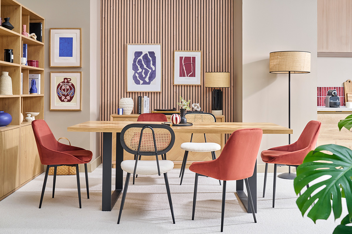 Sala da pranzo con sedie in velluto rosso e metallo nero intorno a un tavolo in legno.