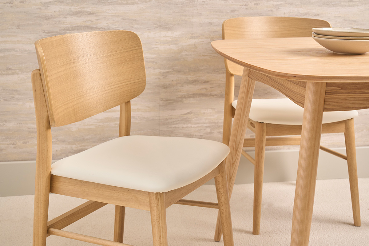 Sedie scandinave bianche e legno chiaro, vista ravvicinata, con un tavolo in legno sullo sfondo.