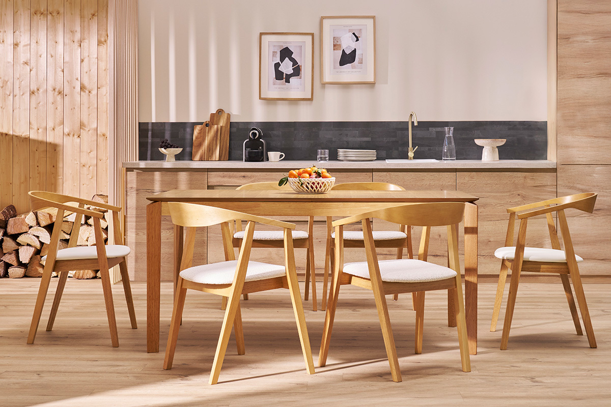 Sedie scandinave BAHIA in legno chiaro e seduta bianca attorno a un tavolo da pranzo in un interno moderno.