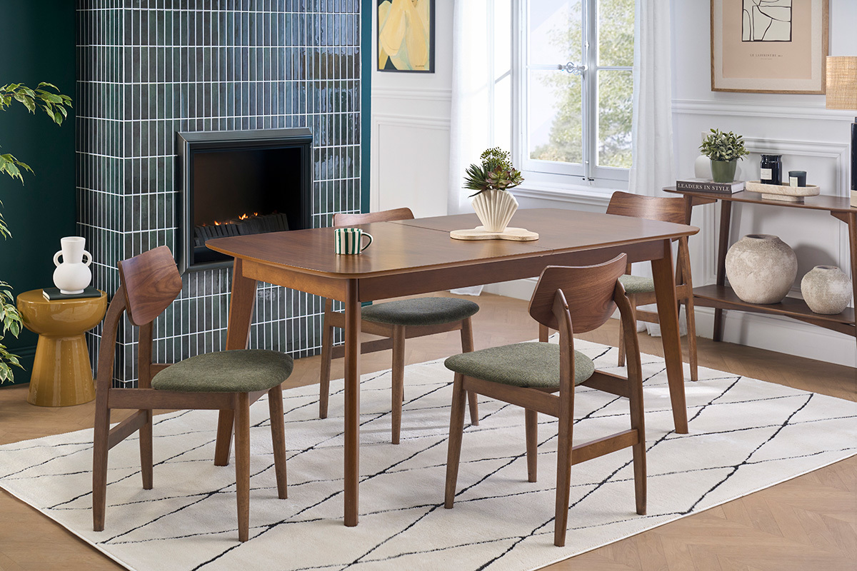 Sedie scandinave in legno scuro e tessuto velluto verde kaki attorno a un tavolo in un interno moderno