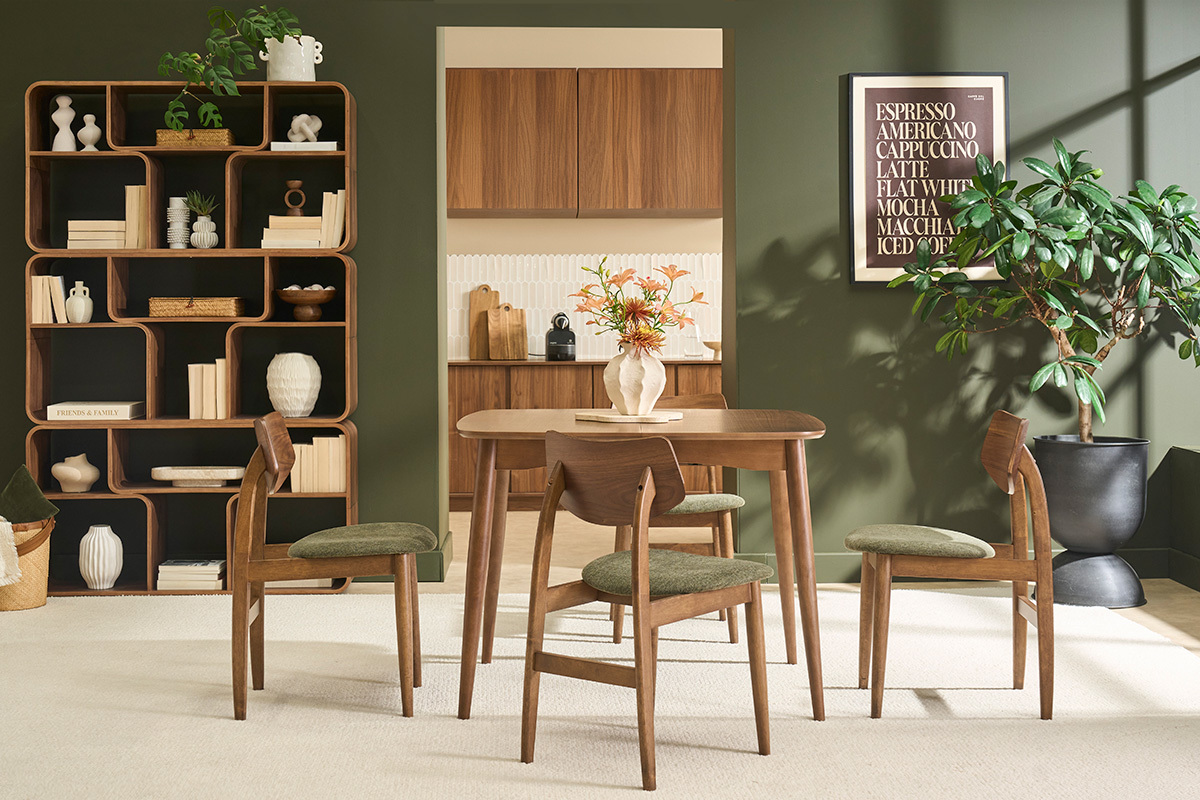 Sedie scandinave in legno scuro e tessuto in velluto verde kaki attorno a un tavolo in un interno moderno.