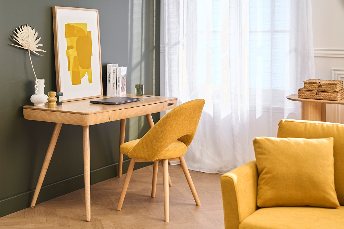 Sedia scandinava in velluto giallo senape e legno chiaro, vista laterale in un ufficio.