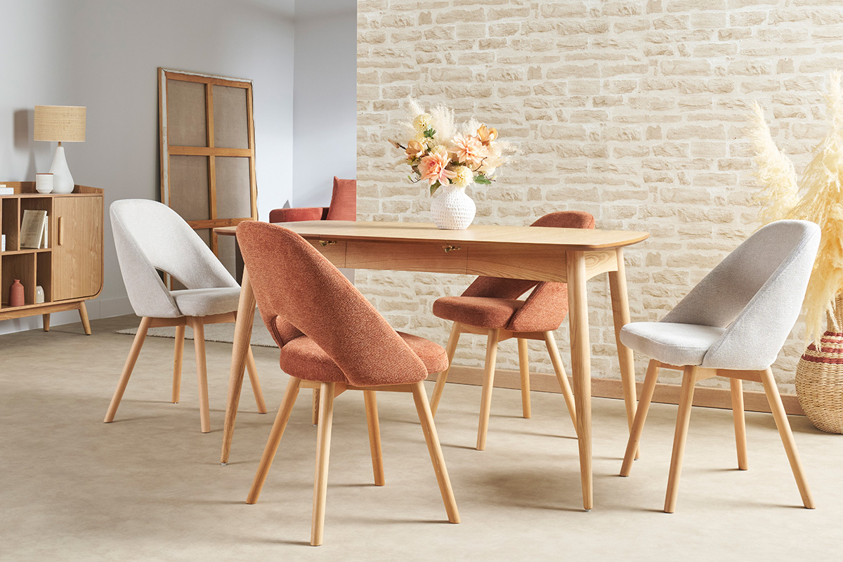 Sala da pranzo con tavolo in legno chiaro e sedie scandinave, vista d'insieme.