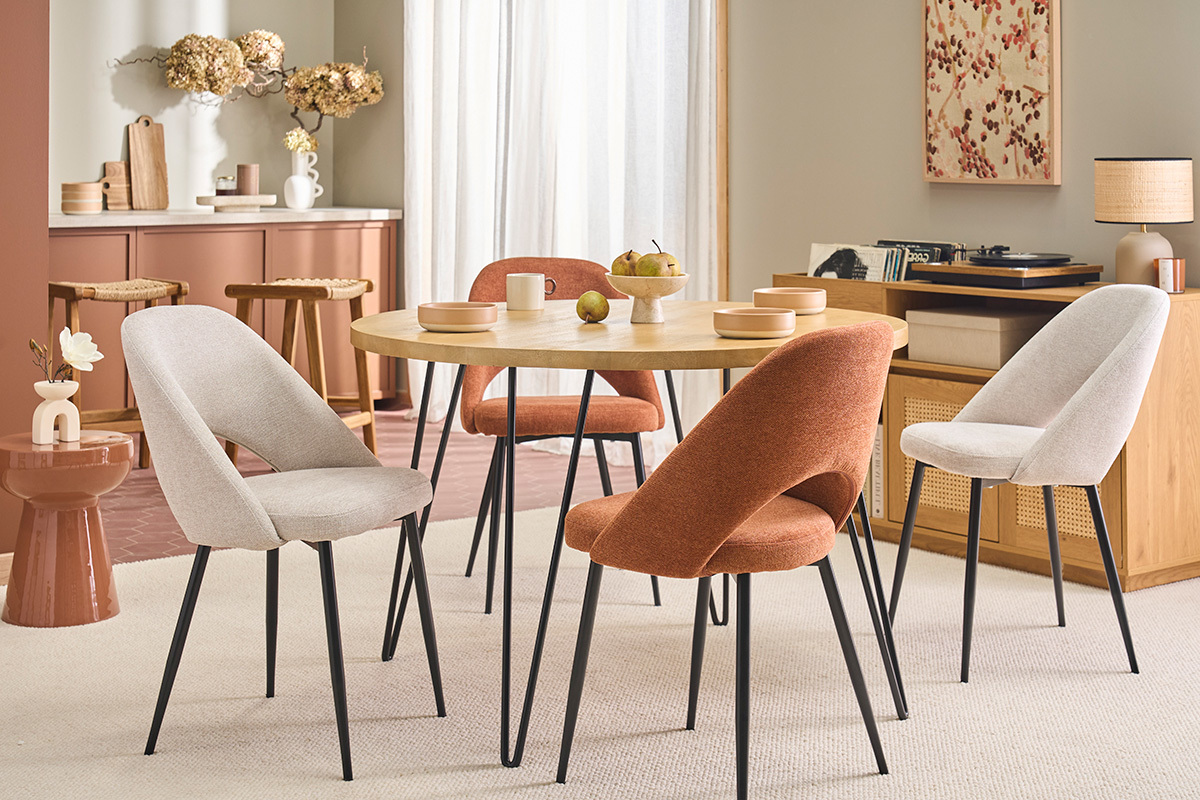 Sedie beige in tessuto effetto velluto, gambe in metallo nero, intorno a un tavolo rotondo.