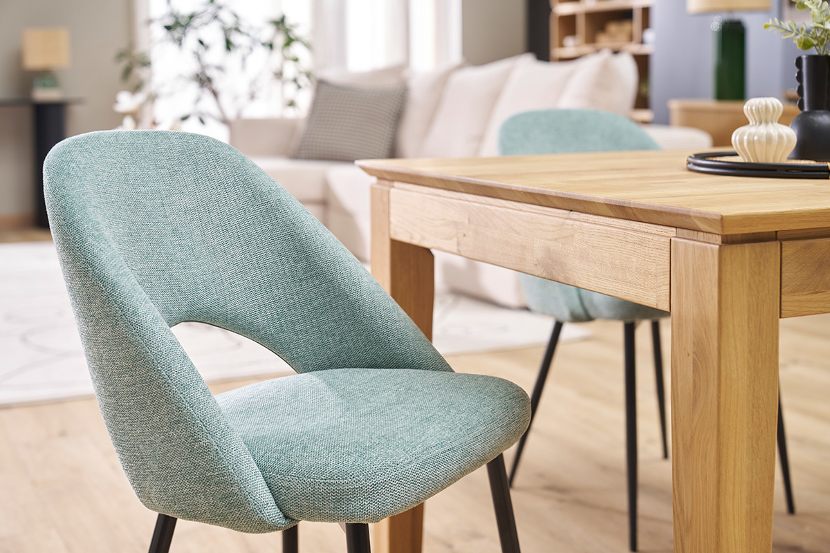 Sedie vintage verde celadon con gambe nere, vicino a un tavolo in legno, in un soggiorno moderno.