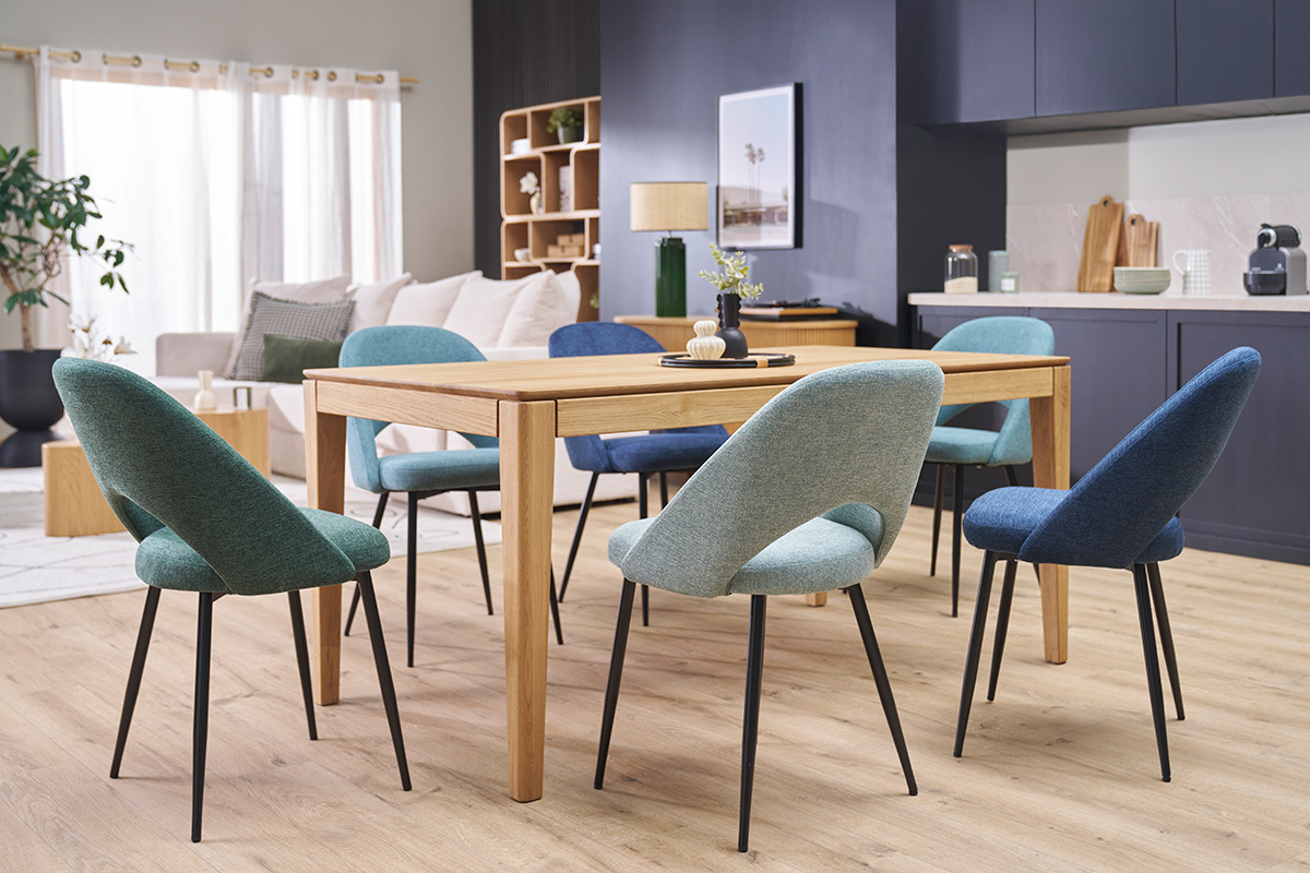 Sedie in velluto color verde celadon con gambe metalliche nere intorno a un tavolo in legno, vista interna.