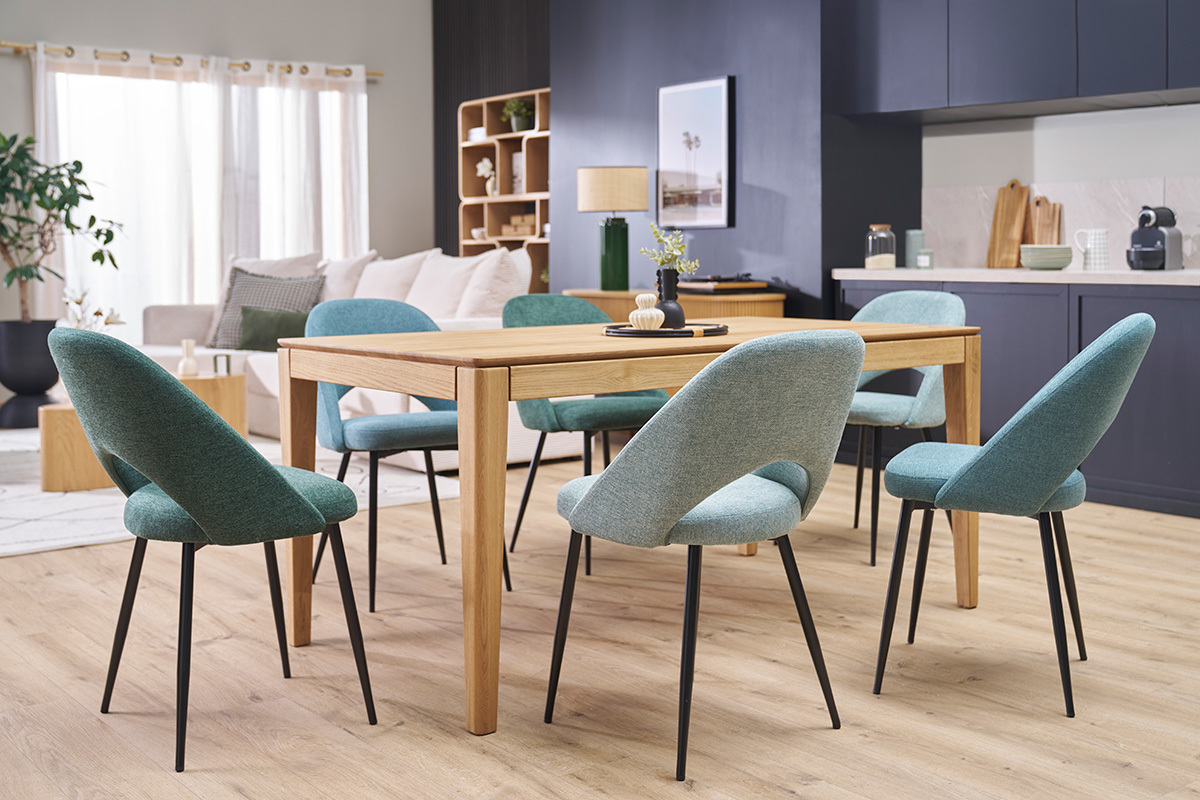 Sedie vintage verde grigio intorno a un tavolo in legno, gambe in metallo nero, vista d'insieme.