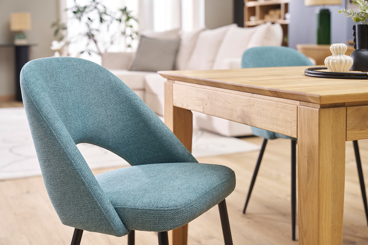 Sedie vintage verde ruggine con gambe in metallo nero, accanto a un tavolo in legno.