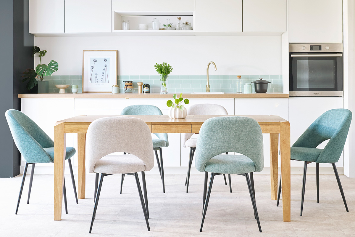 Sedie in tessuto intorno a un tavolo in legno in una cucina moderna.