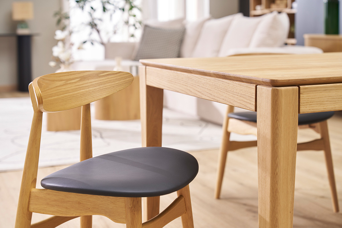 Sedie WALFORD in legno chiaro e nero attorno a un tavolo in legno chiaro, vista di lato.