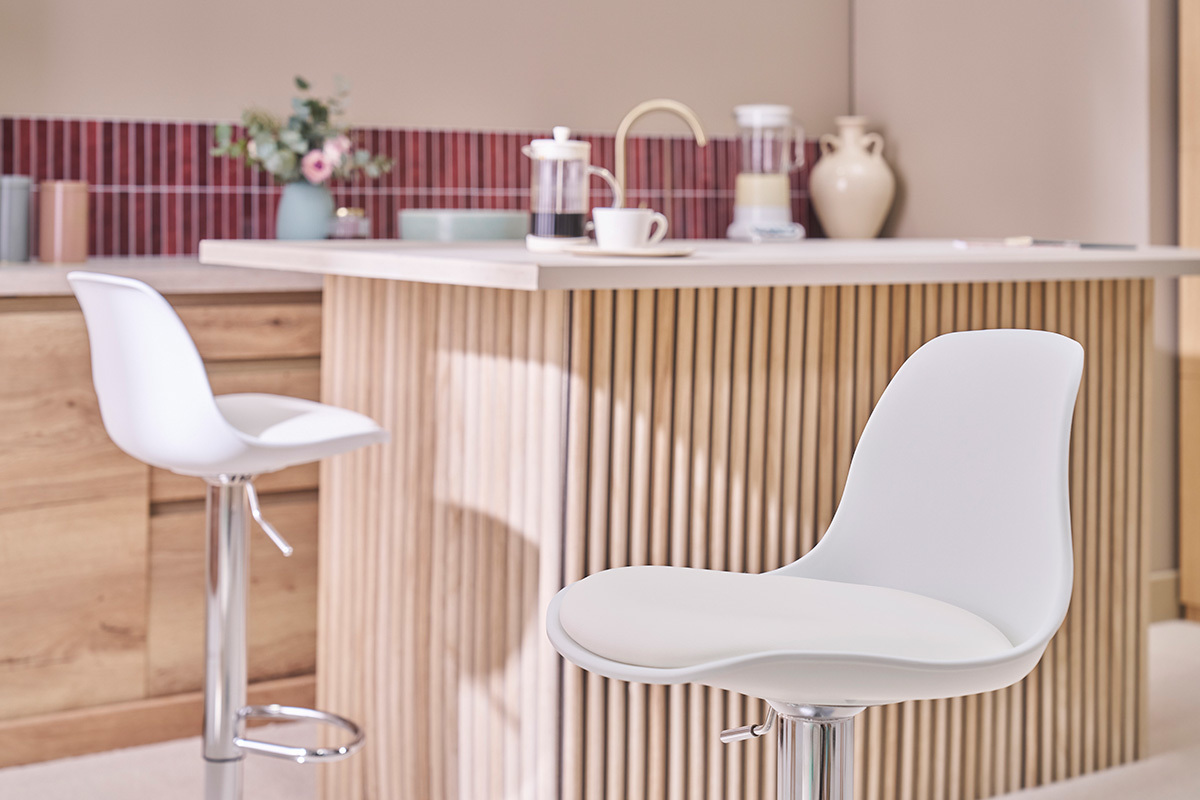 Sgabelli da bar bianchi design STEEVY davanti a un'isola da cucina moderna.