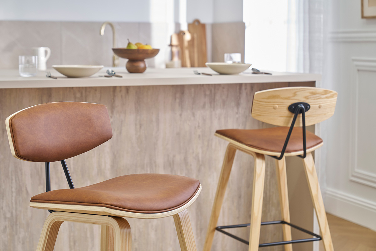 Due sgabelli da bar design marrone e legno chiaro davanti a un bancone da cucina.