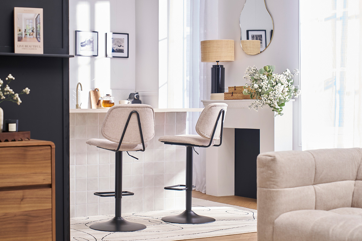 Due sgabelli da bar con seduta in tessuto beige e piede in metallo nero, posizionati davanti a un'isola da cucina.