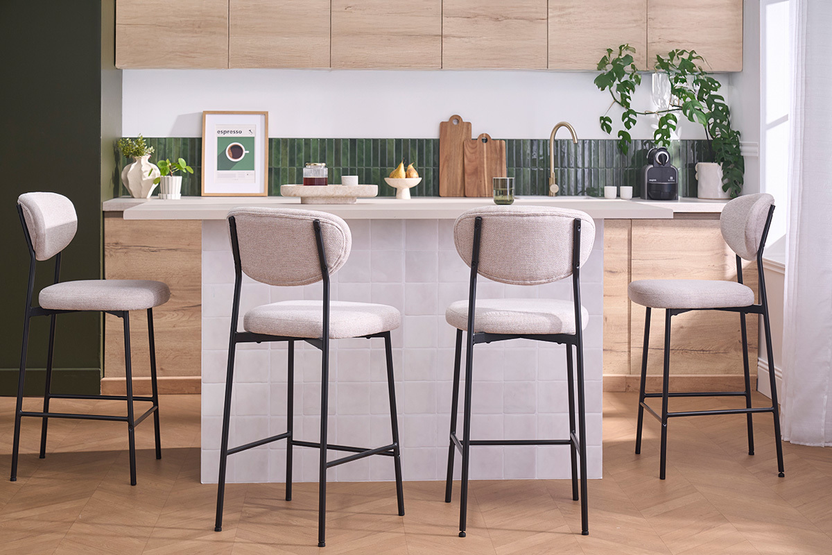Quattro sgabelli da bar in tessuto beige e metallo nero attorno a un'isola in una cucina moderna.