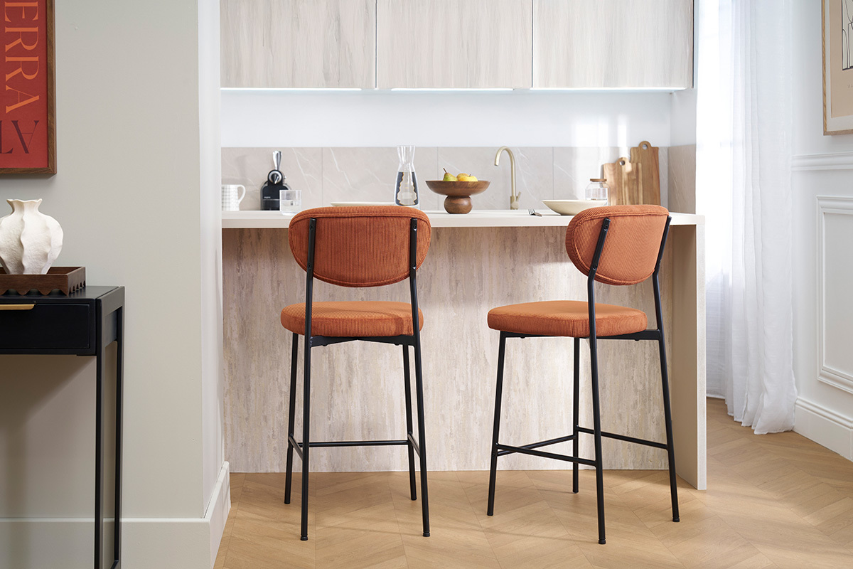 Sgabelli da bar in velluto terra bruciata e metallo nero in una cucina moderna.