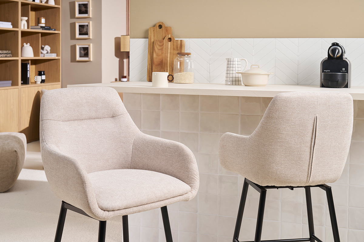 Sgabelli da bar in tessuto beige e metallo nero davanti a un bancone in una cucina.