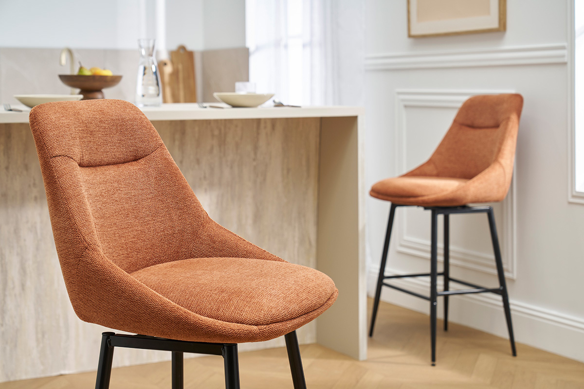 Due sgabelli da bar in tessuto terra bruciata e gambe in metallo, in una cucina moderna.