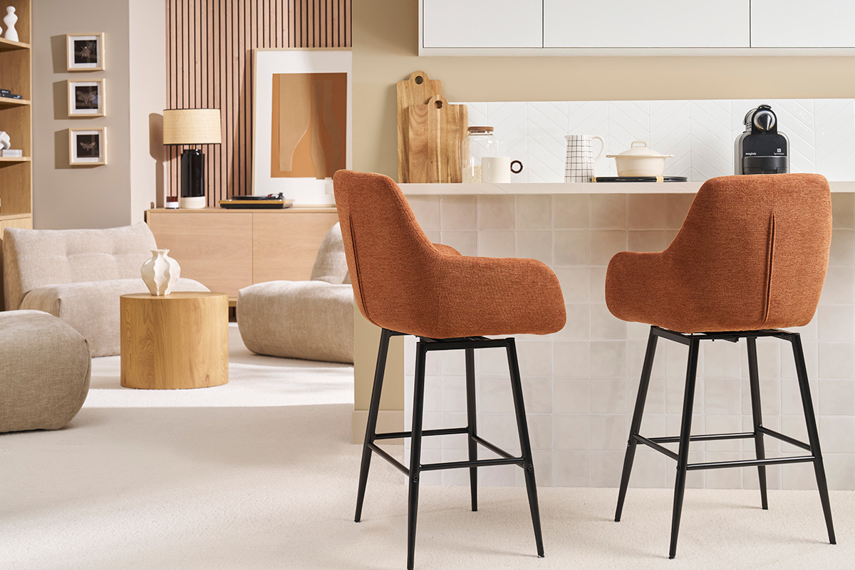 Due sgabelli da bar in tessuto color terra bruciata e metallo nero davanti a un bancone.