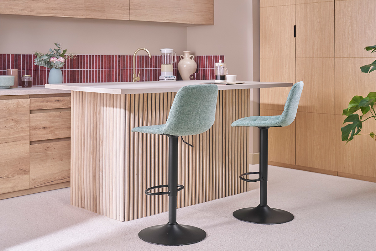 Sgabelli regolabili celadon e metallo di fronte a un bancone da cucina in legno.
