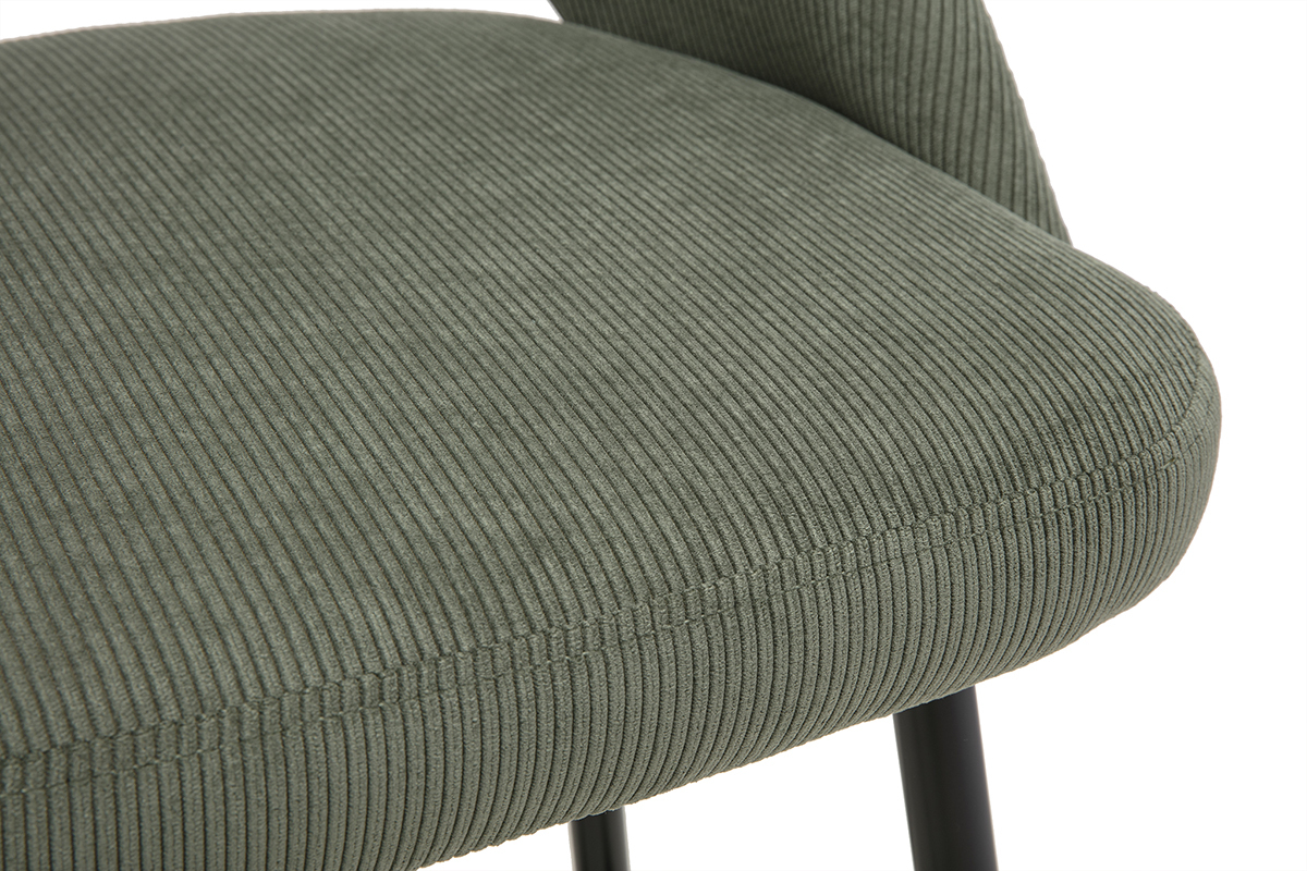 Sgabello da bar in velluto a coste verde cachi, vista ravvicinata, seduta e piedi neri visibili.