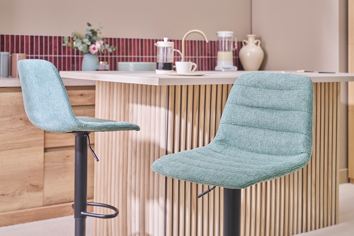 Due sgabelli da bar in tessuto celadon di fronte a un bancone in legno.