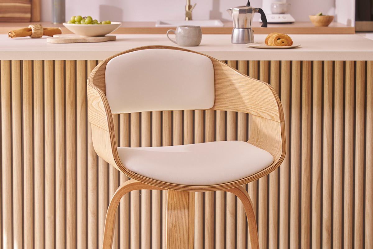 Sgabello da bar scandinavo in legno chiaro con seduta in poliuretano bianco davanti a un bancone da cucina.