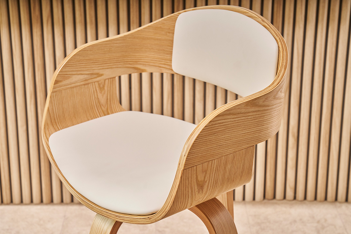 Sgabello da bar scandinavo in legno chiaro con seduta bianca in primo piano.