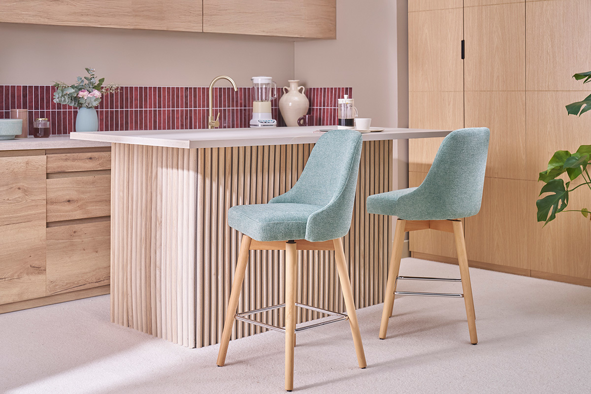 Due sgabelli da bar verdi e in legno davanti a un bancone da cucina.