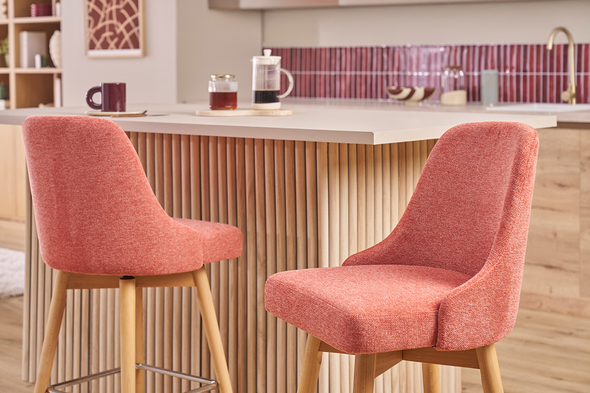 Sgabelli da bar scandinavi in tessuto terracotta e legno davanti a un bancone.