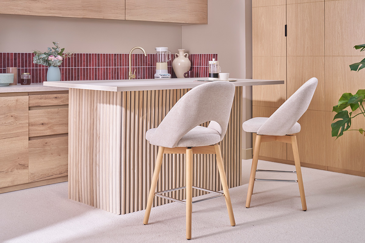 Due sgabelli da bar in tessuto beige con gambe in legno in una cucina.