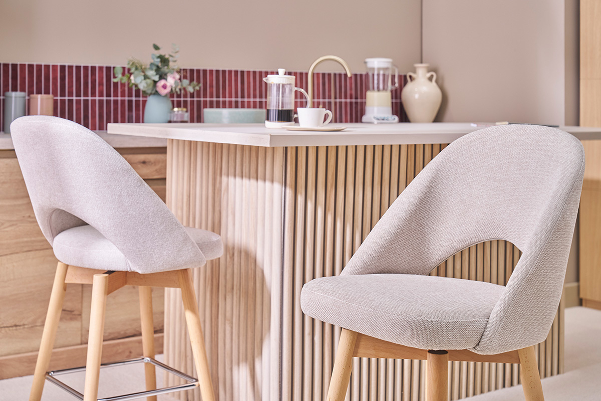 Sgabelli da bar scandinavi beige con gambe in hevea, davanti a un bancone da cucina.
