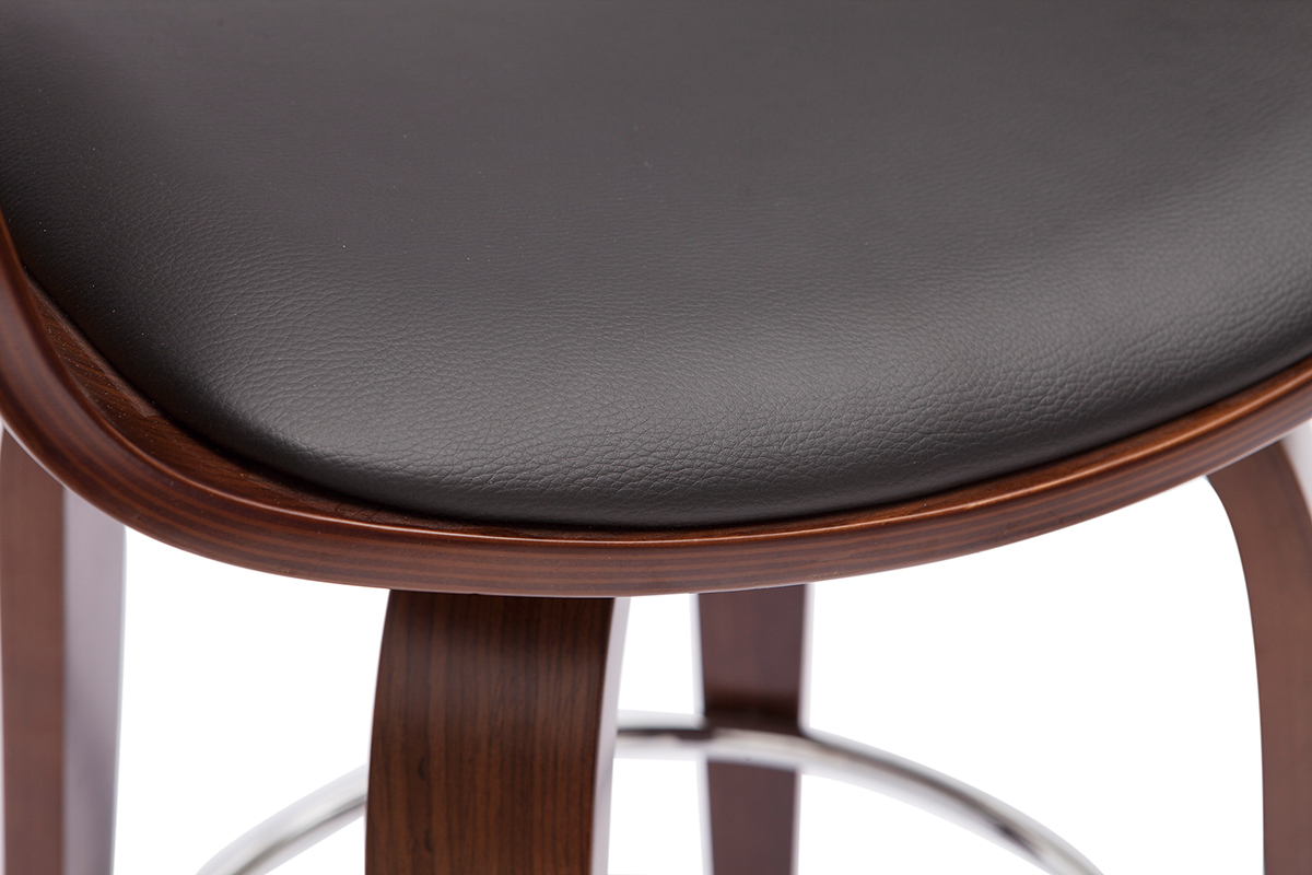 Dettaglio di uno sgabello da bar con seduta nera in poliuretano e struttura in legno tinto noce, poggiapiedi cromato.