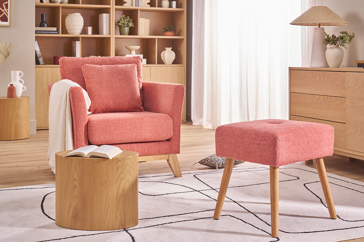 Sgabello basso in tessuto terracotta e legno chiaro, visto accanto a un divano e tavolino.