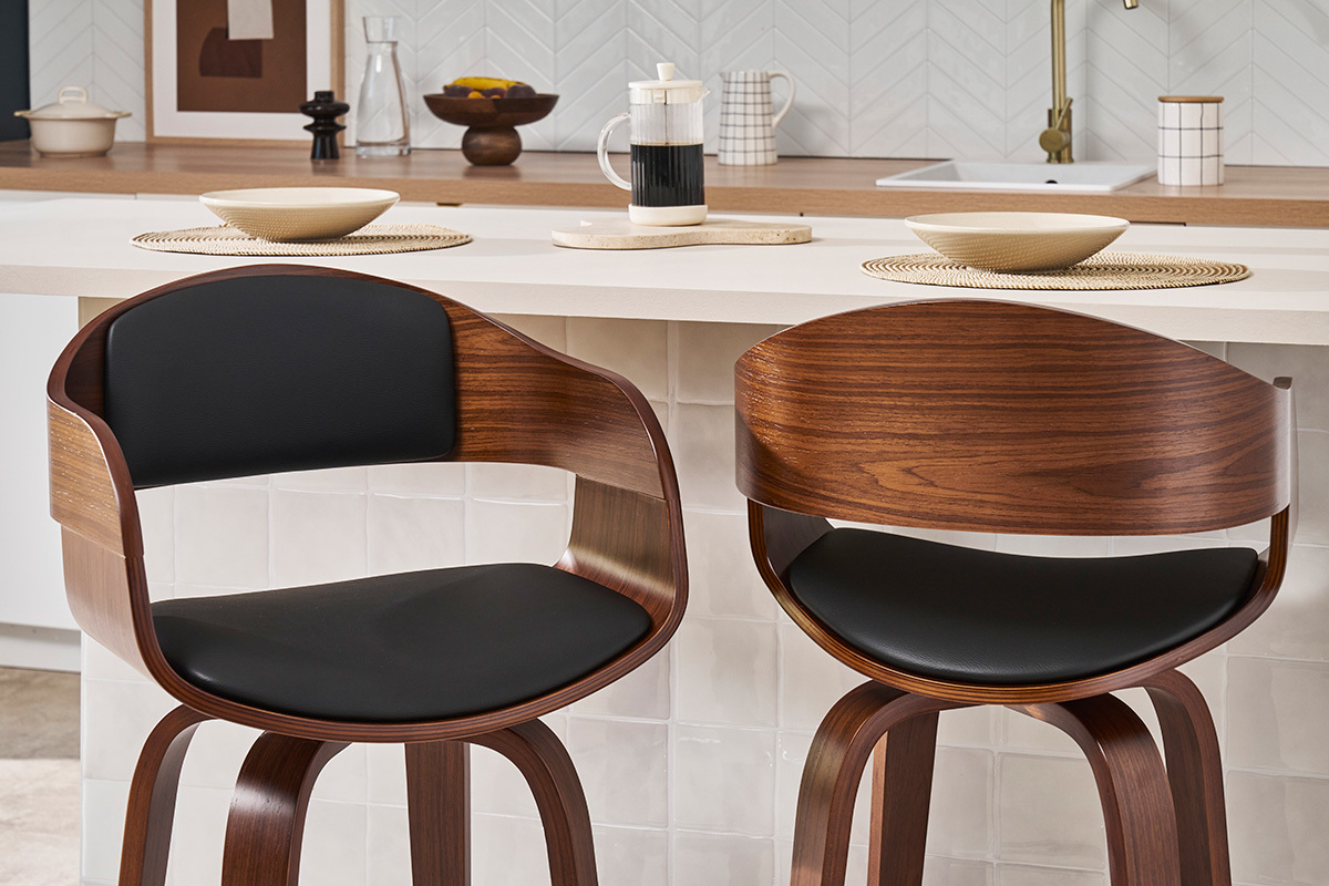 Due sgabelli da bar design in nero e legno scuro, vista frontale, davanti a un bancone da cucina.