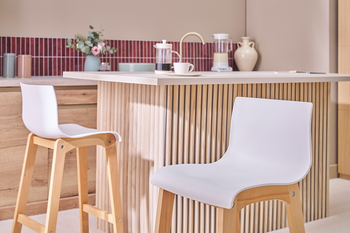Sgabelli da bar design in legno e bianco H65 cm davanti a un'isola centrale.