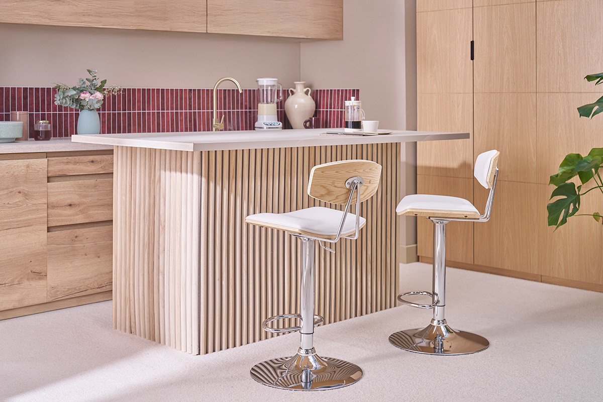 Due sgabelli da bar bianchi e in legno chiaro davanti a un'isola da cucina in legno.