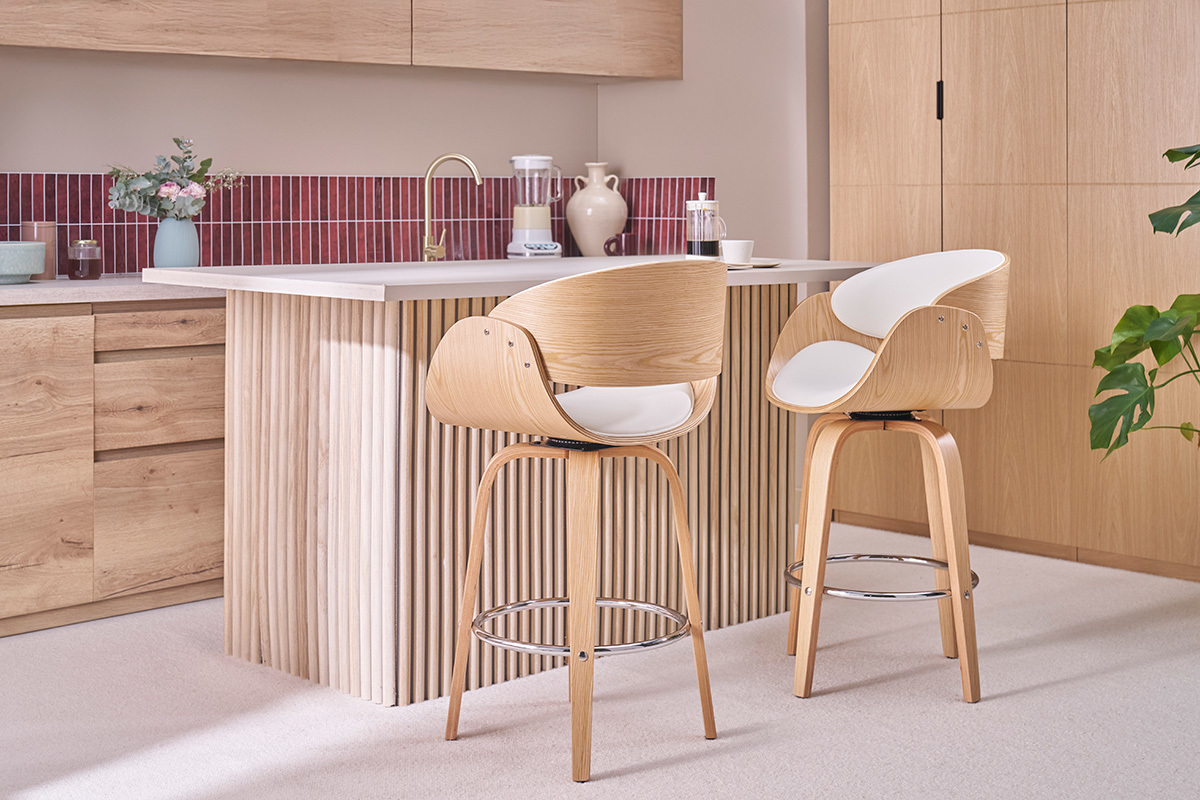 Due sgabelli da bar girevoli bianchi e in legno chiaro davanti a un'isola da cucina.