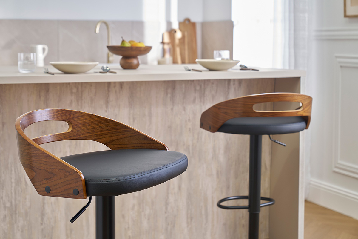 Due sgabelli da bar MANO in legno di noce e pelle nera davanti a un bancone da cucina.