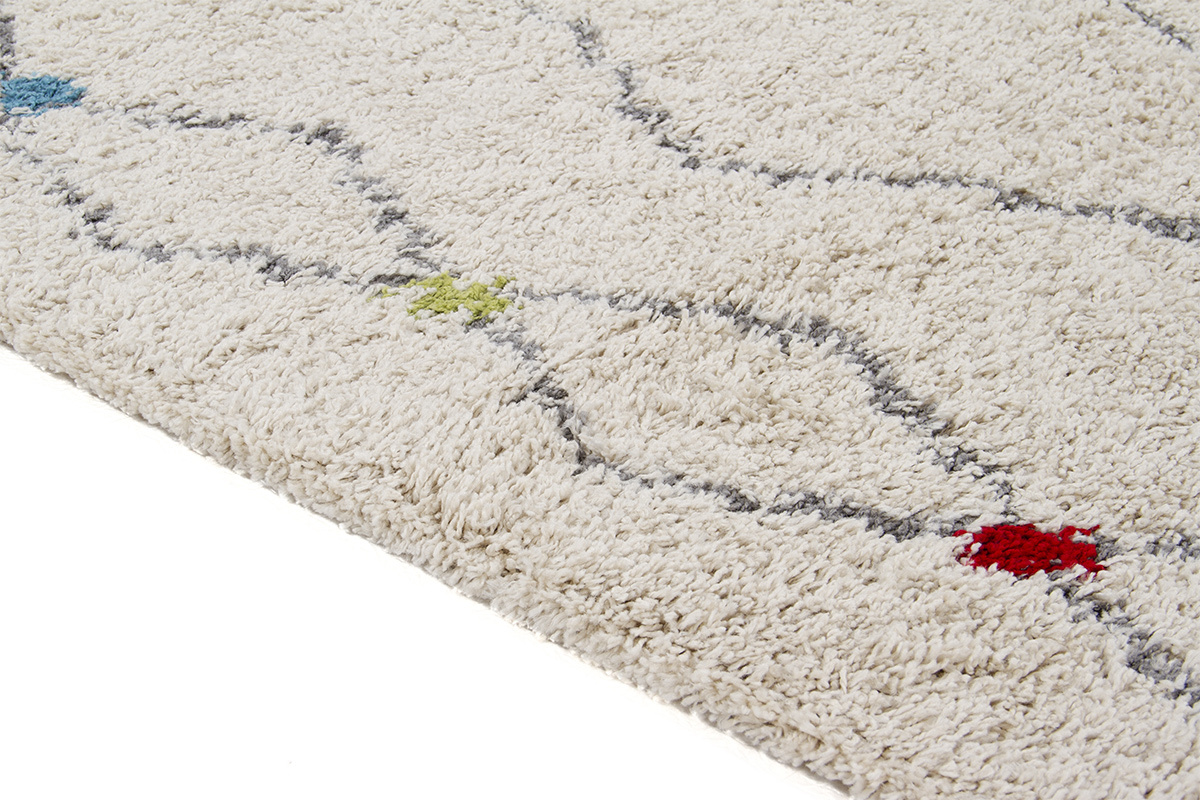 Tappeto beige rettangolare con motivi a rombi e tocchi di colore, vista laterale.