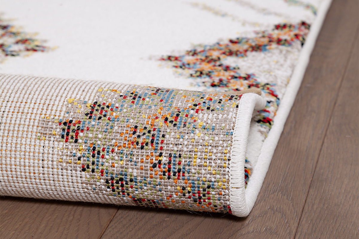 Vista ravvicinata del bordo di un tappeto con motivi colorati su parquet.