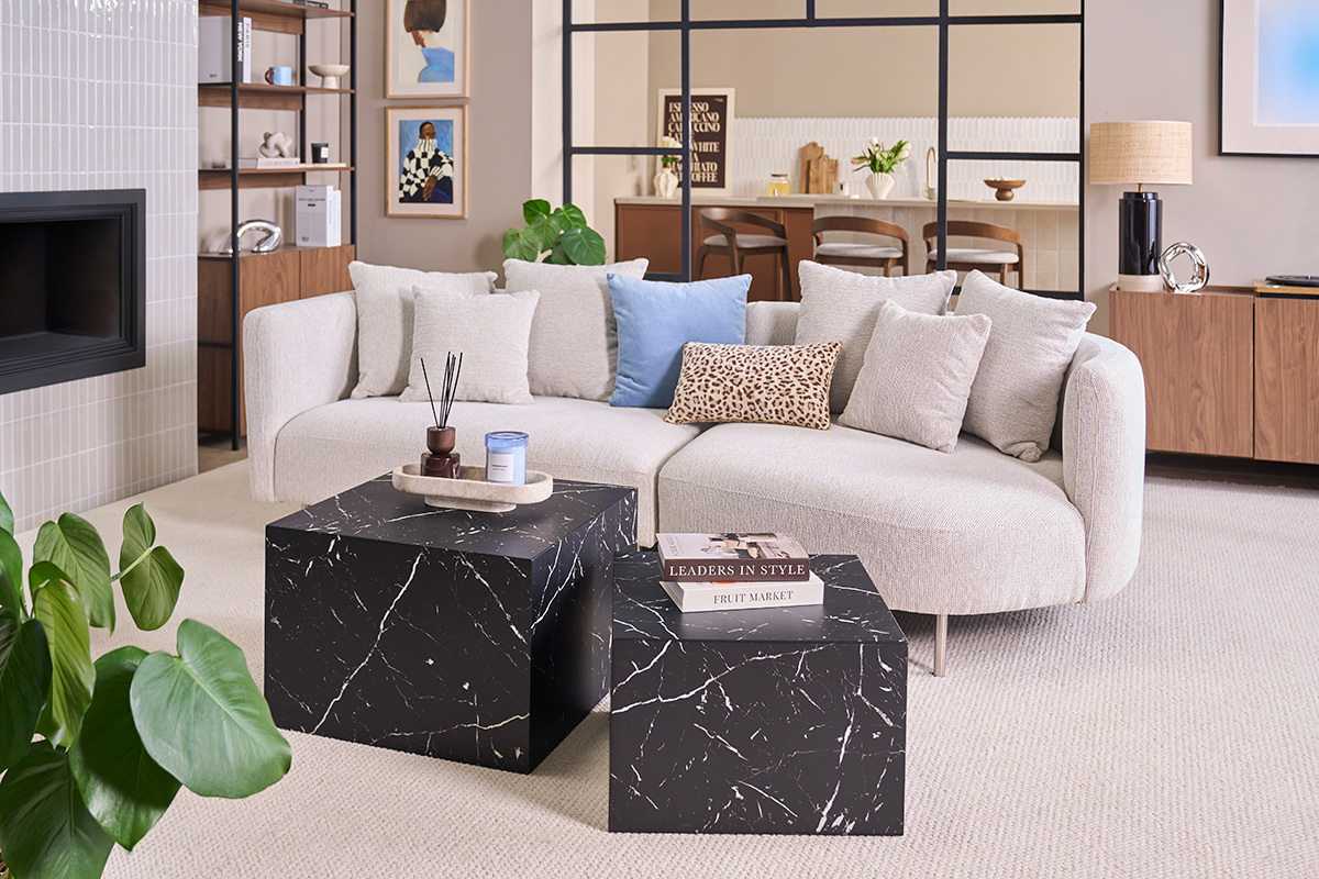 Tavolini bassi impilabili dal design effetto marmo nero, vista frontale in un soggiorno moderno.