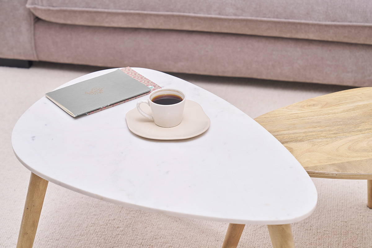 Tavolini nidificati in marmo e legno, con tazza e quaderno.