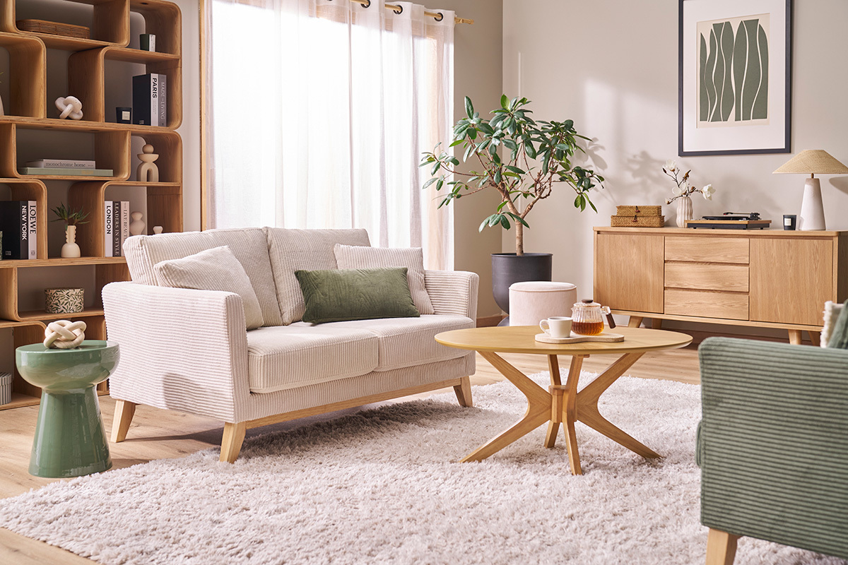 Tavolino rotondo in metallo smaltato verde kaki in un soggiorno con divano e tavolino.