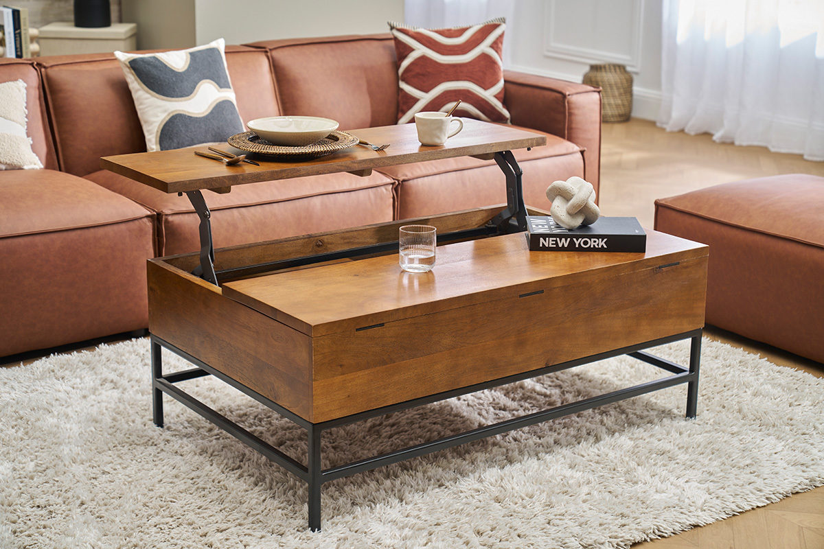 Tavolino basso YPSTER in legno di mango e metallo nero con piano sollevabile, in un soggiorno con divano.